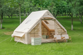 Large beige inflatable ridge tent on green grass with open door showing spacious interior, no text banner
